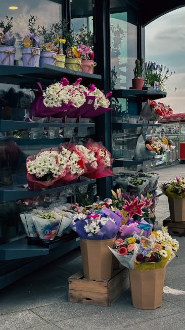 A display of various fresh floral arrangements at a flower shop near Colindale tube station. The arrangement includes vibrant pink and white chrysanthemums, lilies, and roses wrapped in colorful paper